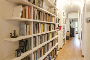 A library with white shelves filled with books and a wooden floor. - Appartamento Belle Arti (Bologna)