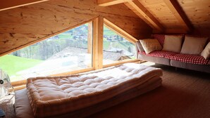 Quarto em estilo loft com uma grande janela, um sofá e um colchão.
