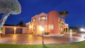 A large, multi-story house with a driveway and a well-maintained lawn.