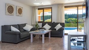 A modern living room with a grey sofa, a coffee table, and a TV mounted on the wall.