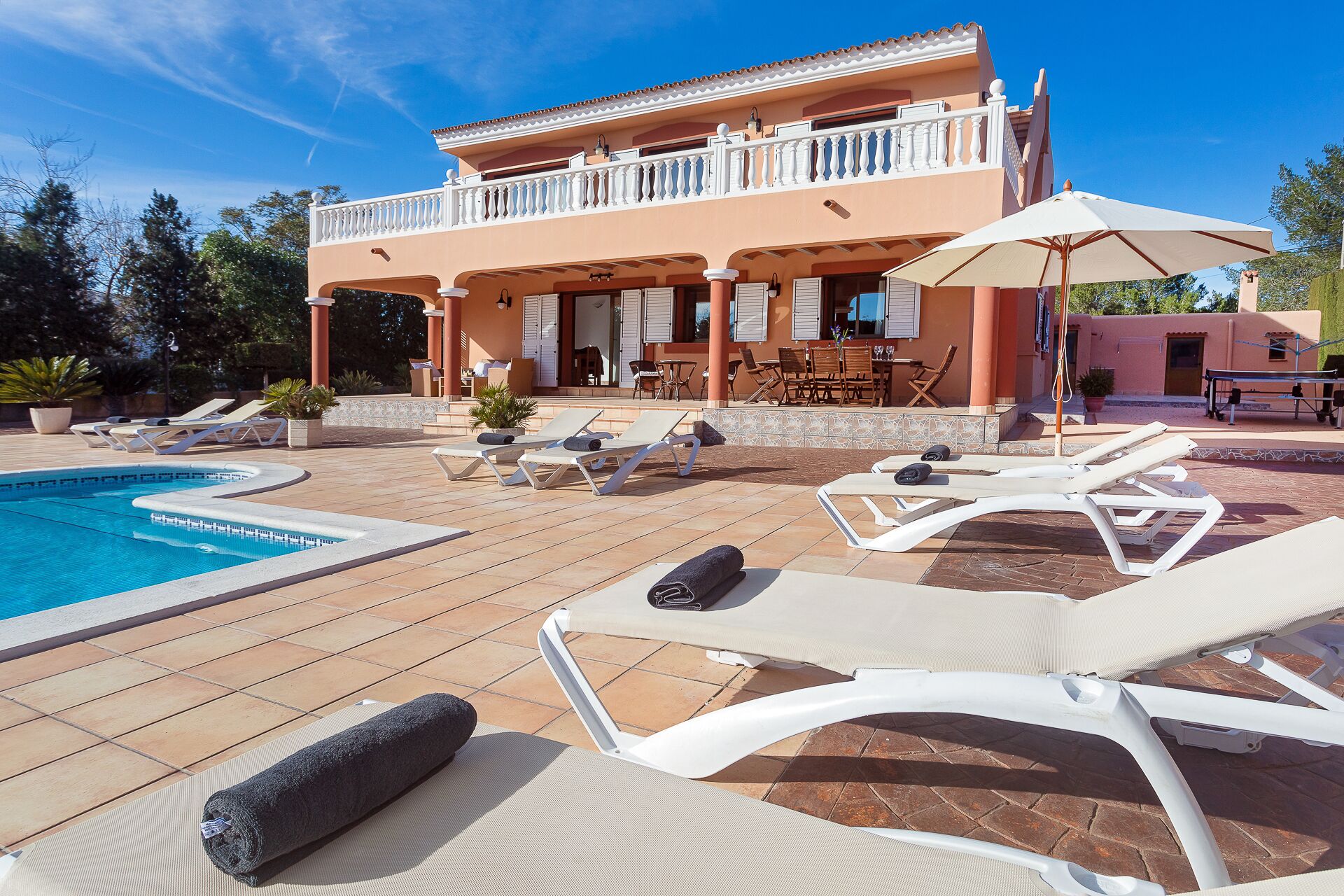 A poolside area with lounge chairs, a pool, and a building with a balcony.