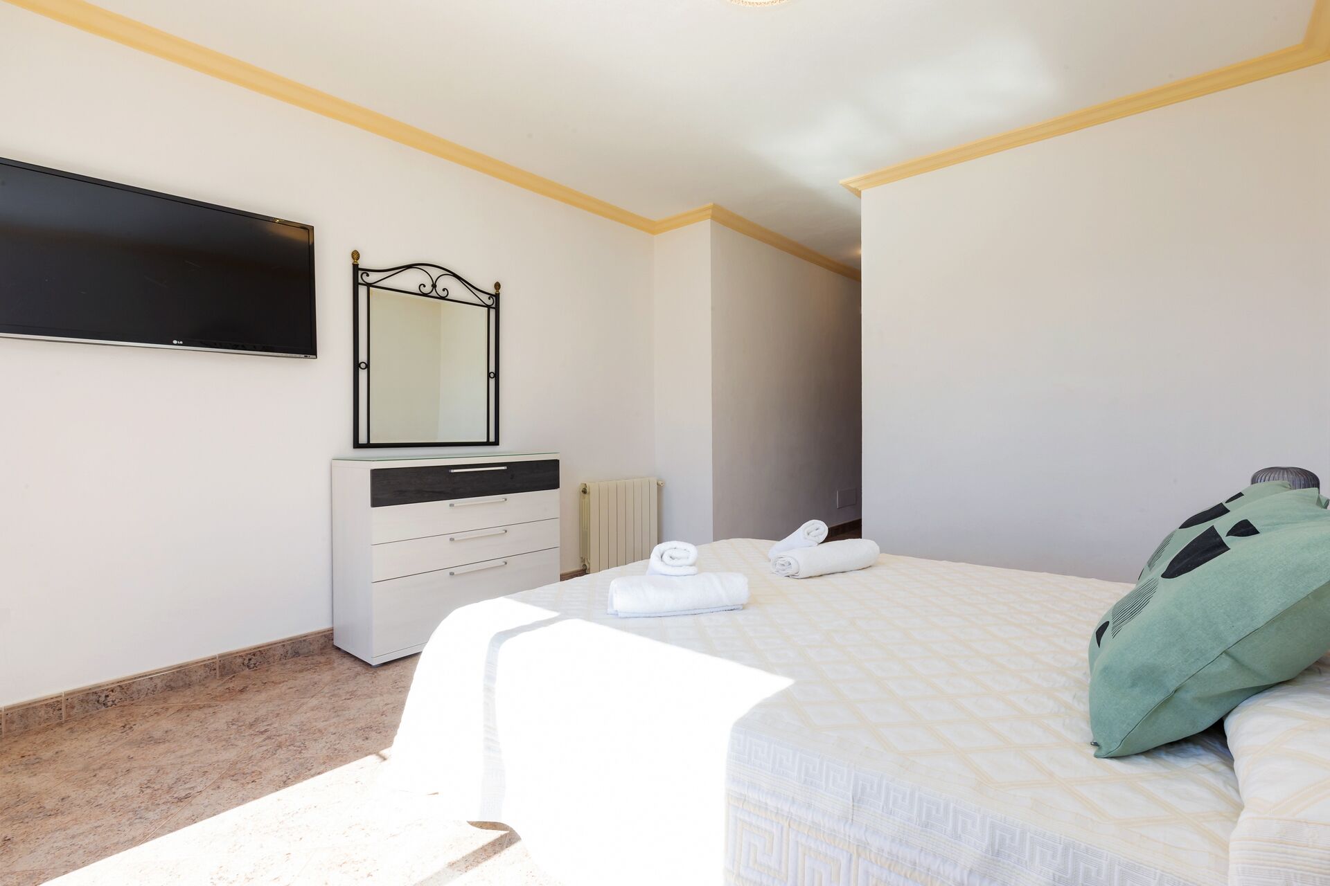 Ein Schlafzimmer mit Bett, Kommode, Spiegel und Heizkörper.