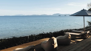 A wooden deck with outdoor seating and a view of the sea.