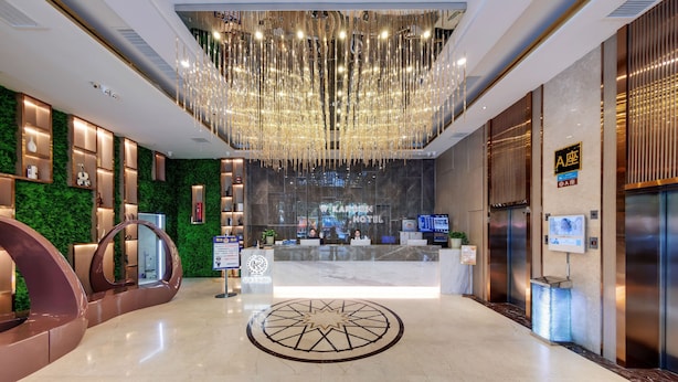 A hotel reception area with a modern chandelier, a reception desk, and a green wall with a vertical garden. - W Kardon Hotel (Guangzhou)
