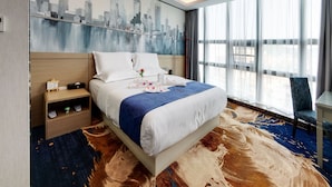 A modern hotel room with a large bed, a cityscape mural on the wall, a wooden nightstand, and a large window with sheer curtains. - W Kardon Hotel (Guangzhou)