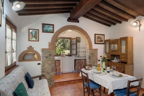 A cozy dining area with a stone archway, a wooden ceiling, and a dining table set for two. - Villa Le Vigne (Bibbona)