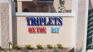A sign for "TRIPLETS ON THE BAY" with a beige wall and a green gate. - Fantastic apartment in Montego Bay (Montego Bay)