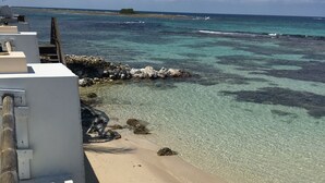 A beach with clear turquoise water, a sandy shore, and a wooden walkway leading to the water. - Fantastic apartment in Montego Bay (Montego Bay)