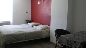 A bedroom with a bed, a table, and a chair. - Appart Hotel de la Paix (Barcelonnette)
