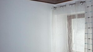 Een badkamer met douchegordijn, handdoekhouder en een zichtbaar raam met gordijn.