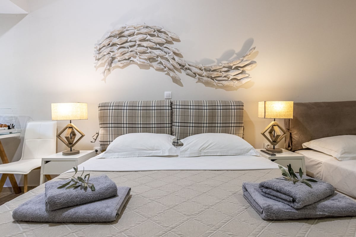 A hotel room with a large bed, two bedside tables, a wall art piece, and two lamps.