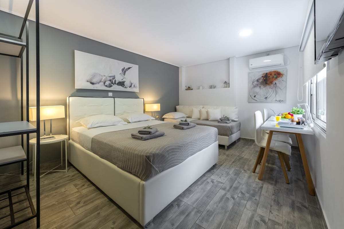 A modern bedroom with a large bed, bedside tables, a desk, and a chair.