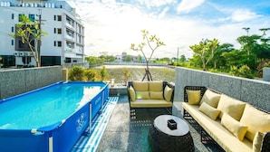 A rooftop pool area with a blue pool, a beige sofa, and a round table. - Milk Homestay (Wujie)