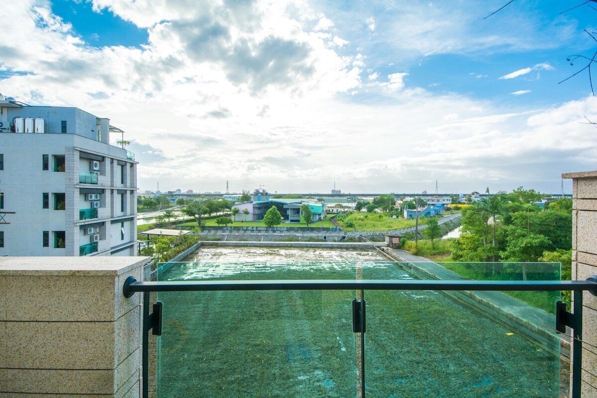 A view from a balcony overlooking a swimming pool area with buildings in the background.