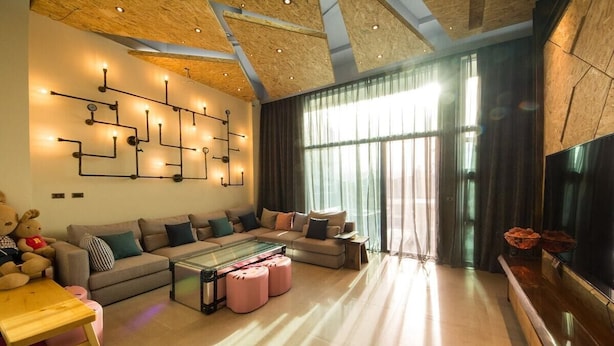 A modern living room with a sectional sofa, a glass coffee table, and a flat-screen TV. - Milk Homestay (Wujie)