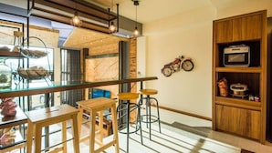 A modern kitchen with wooden accents, a glass bar, and bar stools. - Milk Homestay (Wujie)