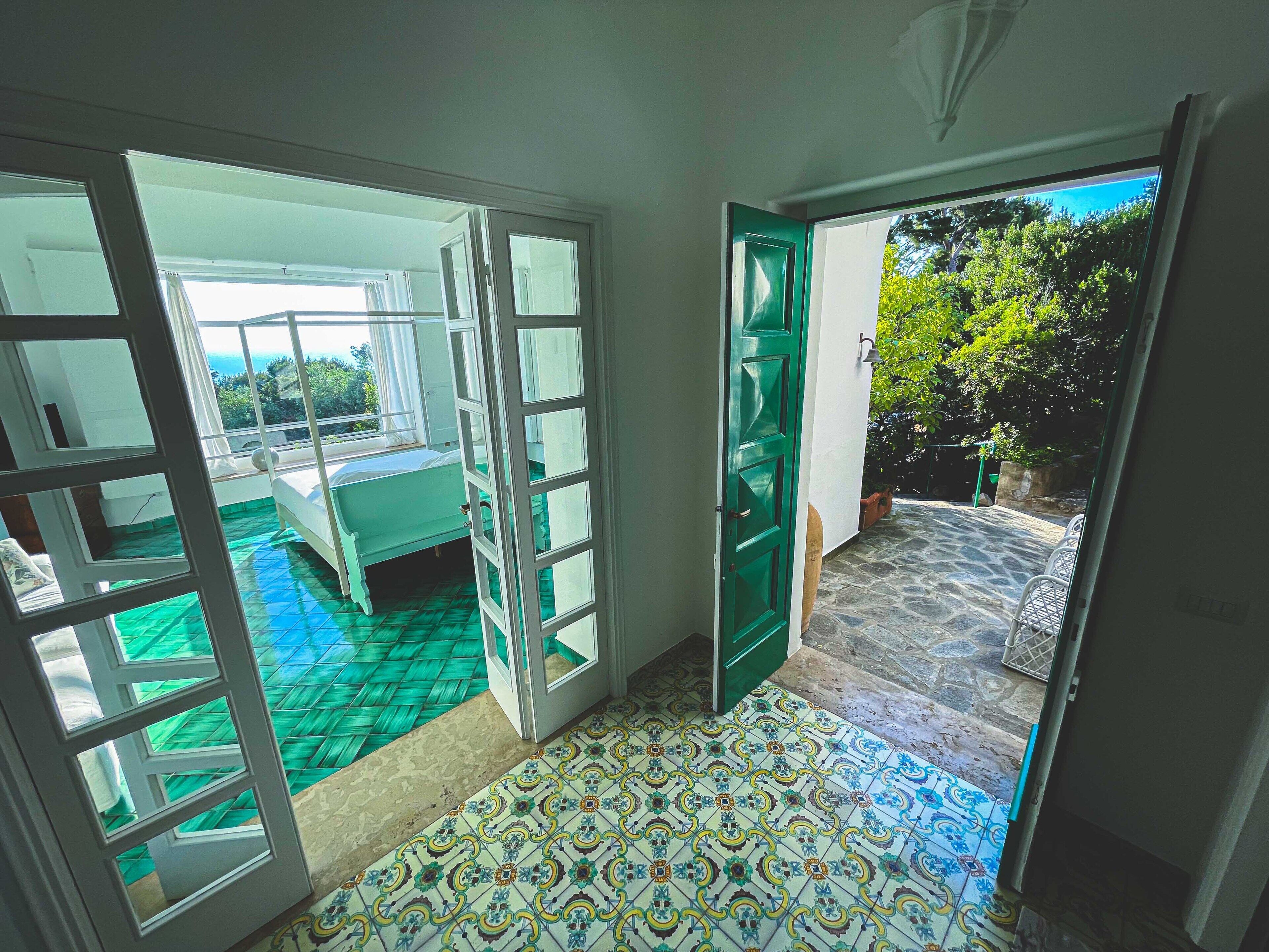 Una habitación con una cama, una puerta verde y vistas al exterior.