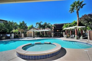 A swimming pool with a hot tub, lounge chairs, and a covered seating area. - PRIVATE, FULLY FURNISHED CONDO IN GATED COMMUNITY OF SEVEN HILLS, HENDERSON NV. (Henderson)