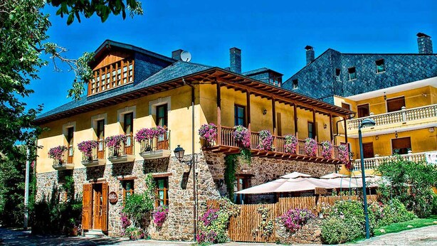 Un edificio tradizionale con pareti in pietra, balconi in legno con fioriere e un ingresso in pietra.
