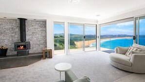 Una sala de estar moderna con chimenea, un sofá y vistas al océano.