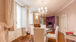 A spacious living room with a wooden floor, white furniture, a chandelier, and a purple accent wall. - LOFT IN THE CENTER OF BARI NEAR THE CHURCH OF SAINT NICHOLAS  (Bari)