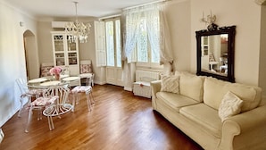 A spacious living room with a wooden floor, a white sofa, a dining table with chairs, and a chandelier. - LOFT IN THE CENTER OF BARI NEAR THE CHURCH OF SAINT NICHOLAS  (Bari)