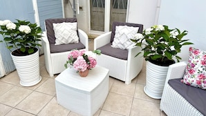 A patio area with wicker furniture, including two chairs and a small table, each with cushions. There are potted plants with flowers on the table and beside the chairs. - LOFT IN THE CENTER OF BARI NEAR THE CHURCH OF SAINT NICHOLAS  (Bari)