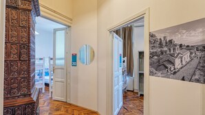 A hallway with a herringbone floor, a mirror, and a black and white photograph on the wall. - Booking BnB (Belgrade)