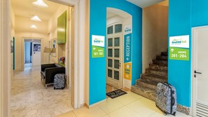 A hotel reception area with a blue wall, a staircase, and a zebra-patterned suitcase. - Booking BnB (Belgrade)