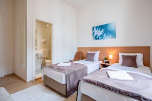 Habitación de hotel con dos camas, un baño y un cuadro en la pared.