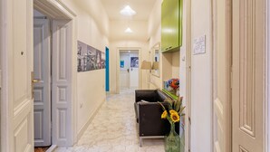 A hallway with a marble floor, a black leather sofa, a vase with sunflowers, and a green cabinet. - Booking BnB (Belgrade)