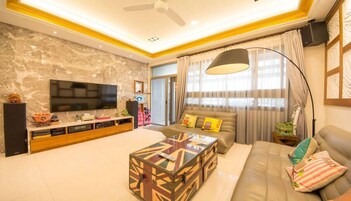 Una sala de estar moderna con un televisor de pantalla plana, un sofá, una mesa de centro y un amplio ventanal con cortinas.