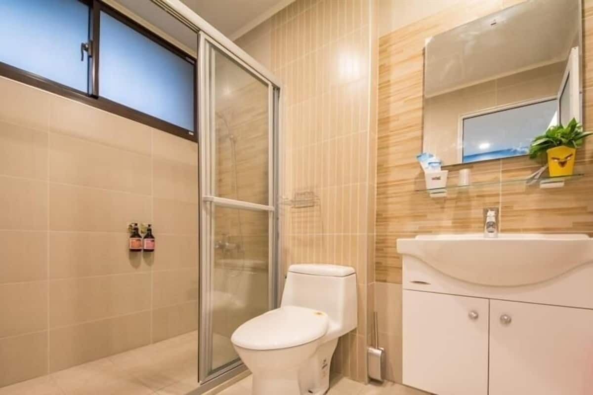 A modern bathroom with a toilet, shower, and sink.