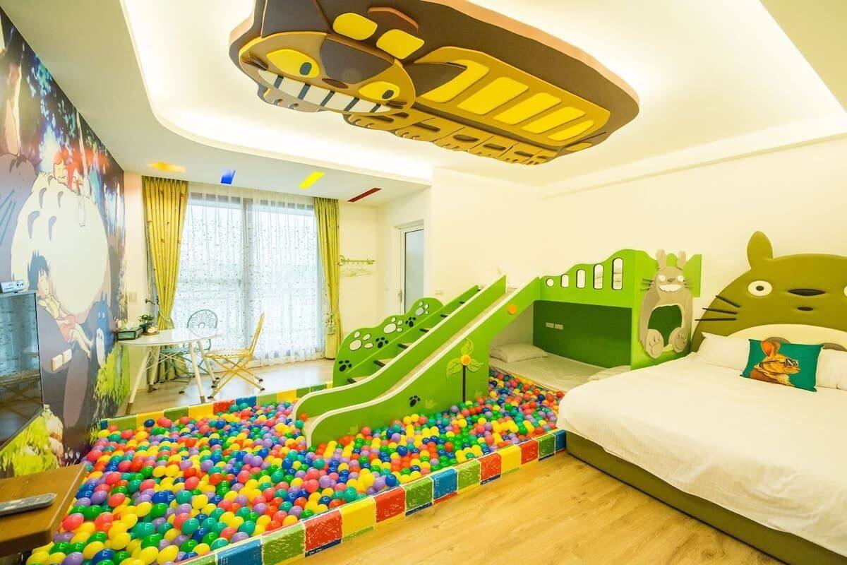 A children's room with a ball pit, a slide, and a bed with a cartoon cat design.