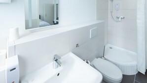 A modern bathroom with a white sink, toilet, and shower. - Dreams Bielefeld (Bielefeld)
