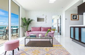 A modern living room with a pink sofa, a glass coffee table, and a view of the city.