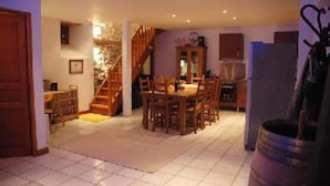 A dining area with a wooden table and chairs, a staircase leading to another level, and a refrigerator in the background. - House / Villa - VIGNEC (Vignec)