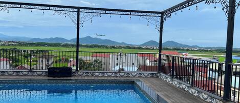 Una piscina con vistas a un campo verde y montañas a lo lejos.