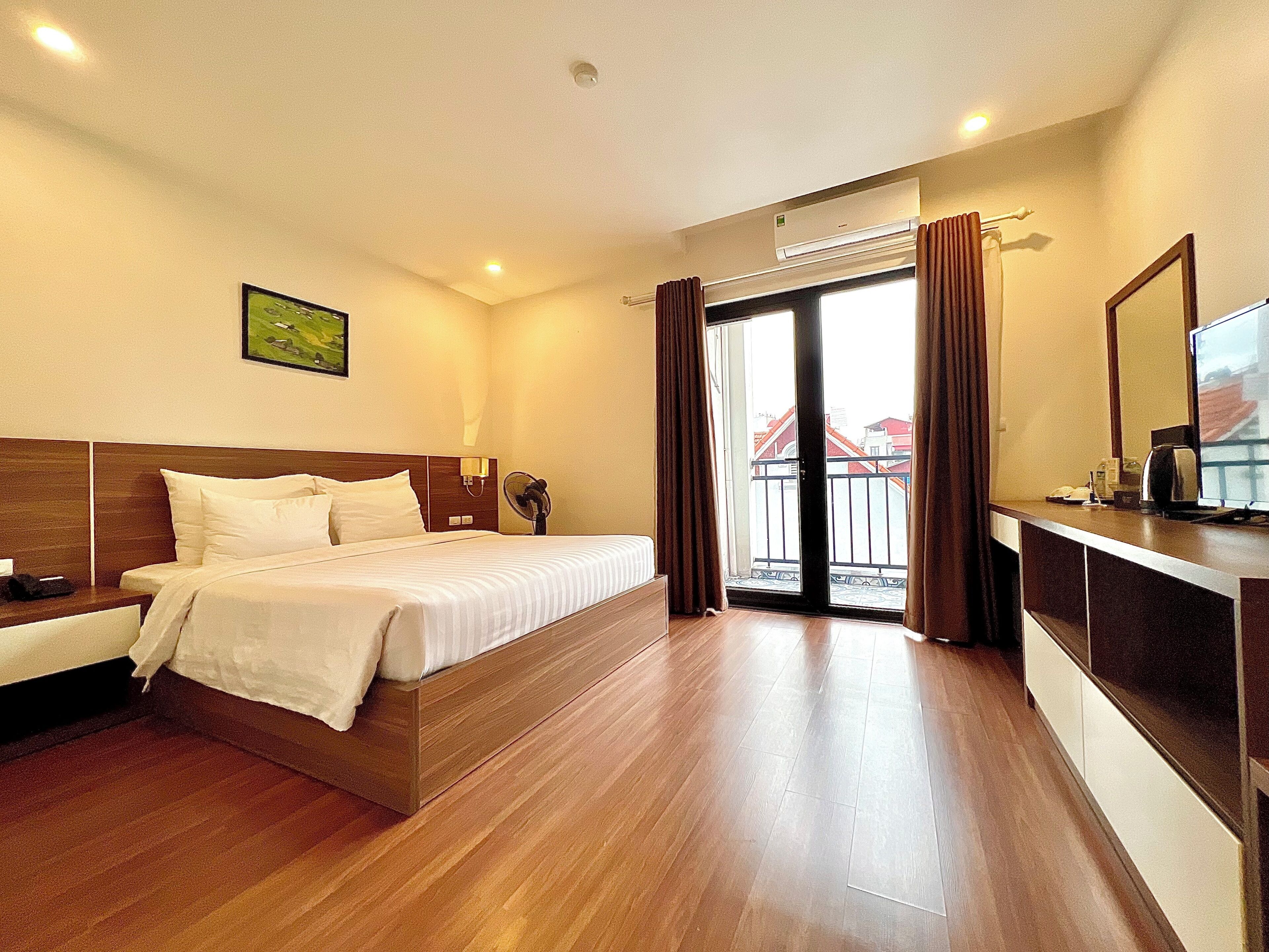Een hotelkamer met een bed, nachtkastje en uitzicht.