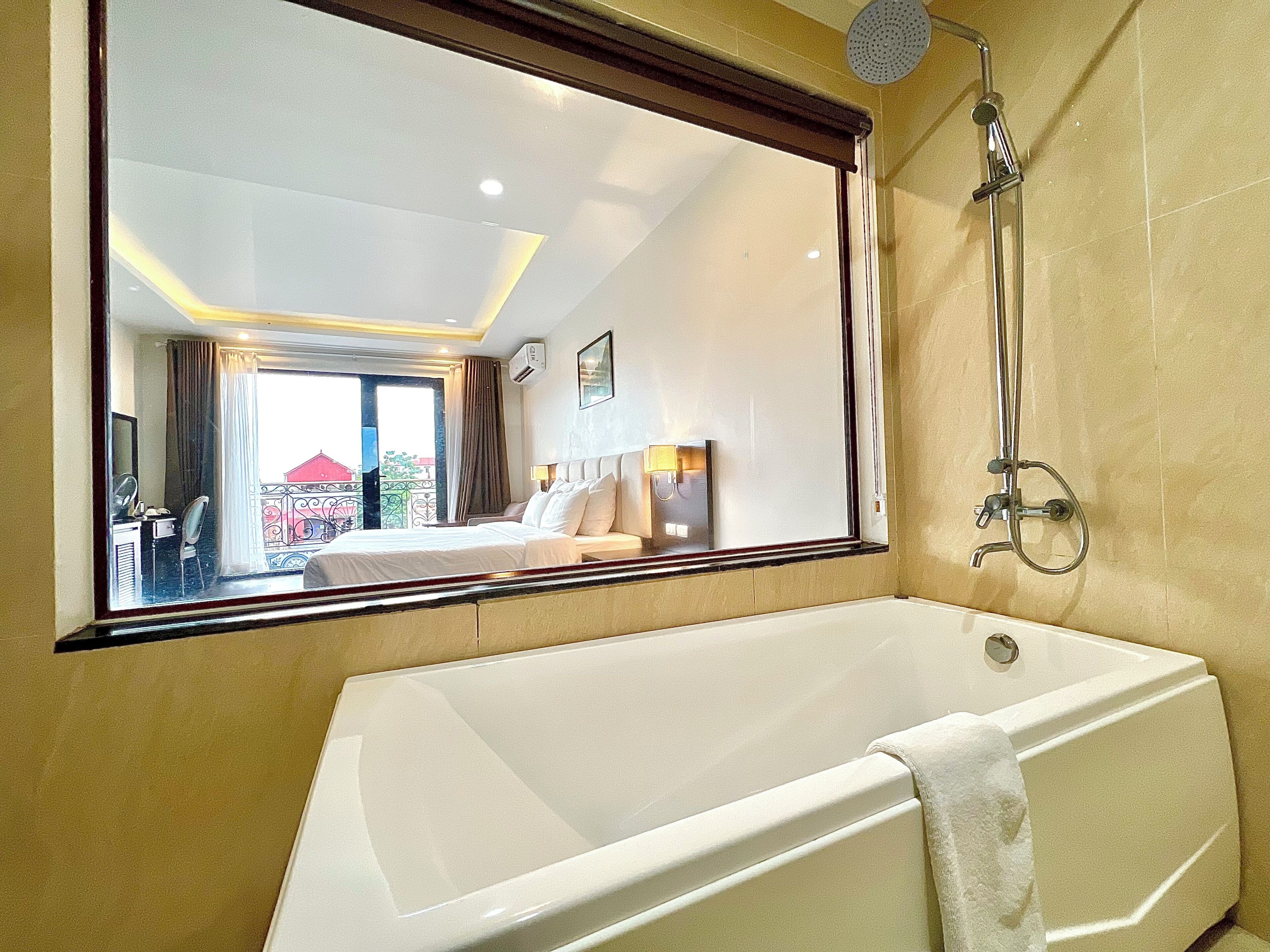 A hotel bathroom with a bathtub, a shower, and a large mirror reflecting the room.