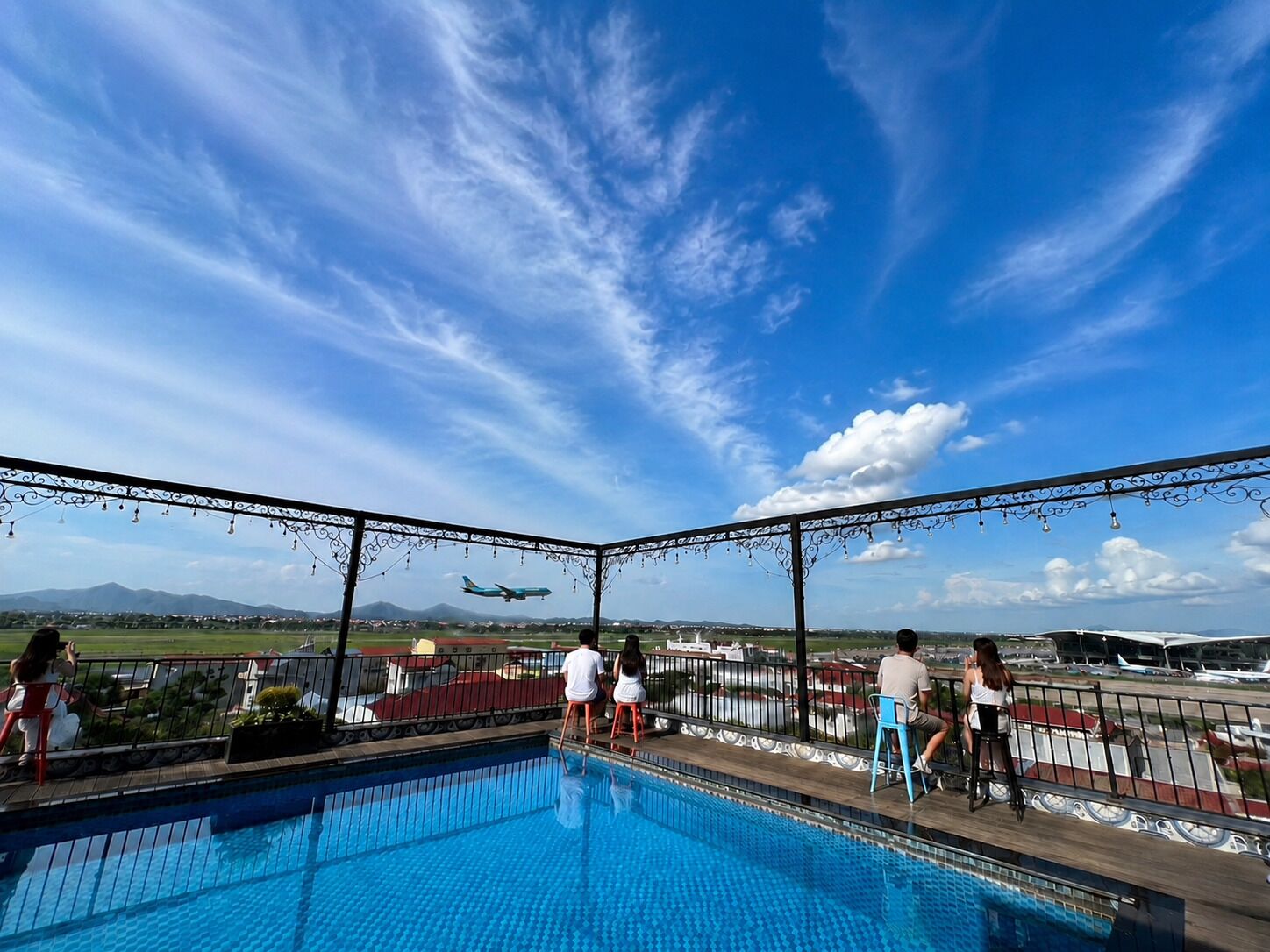 A pool area with a view of an airport and mountains in the background.