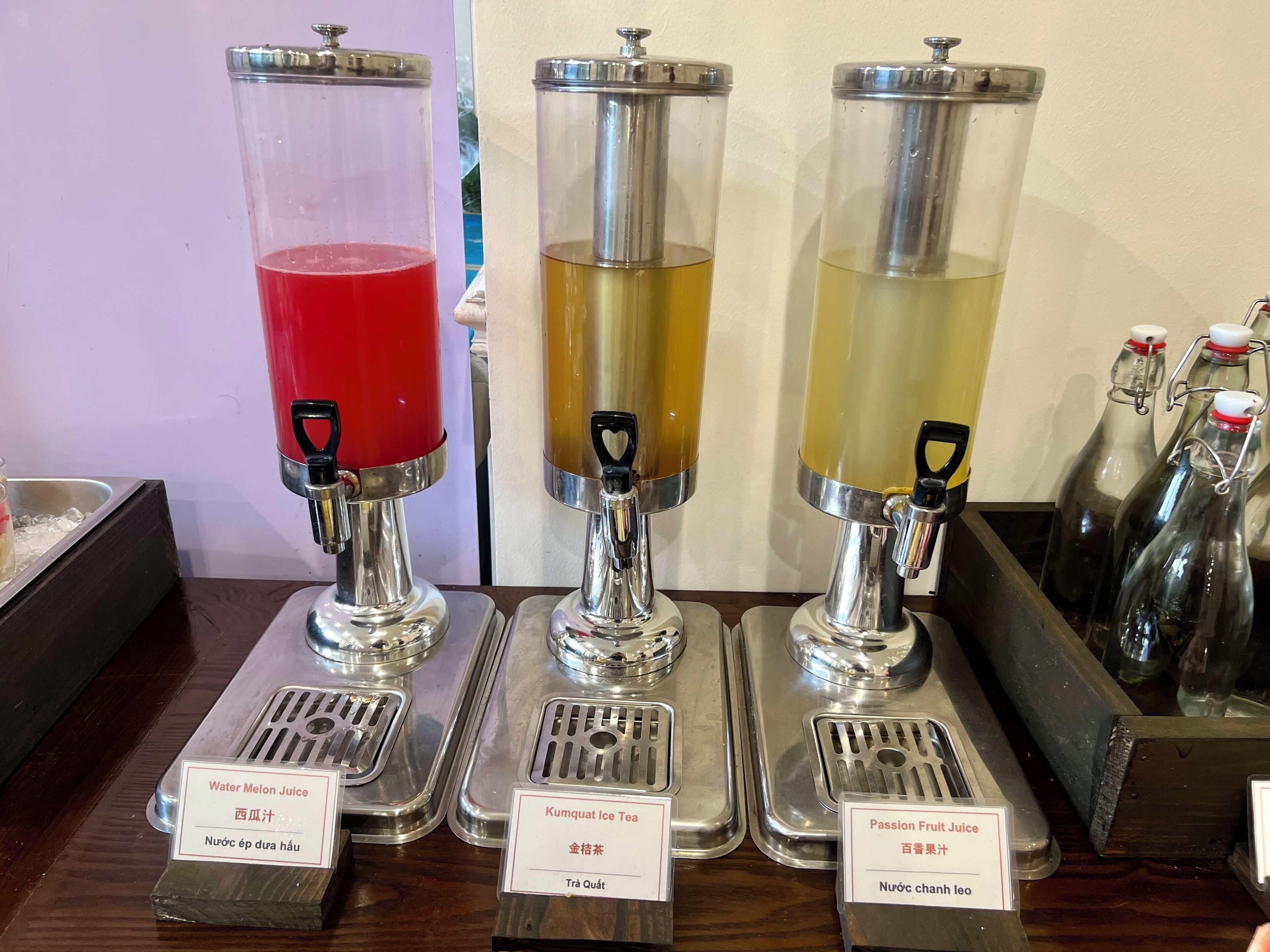 Three beverage dispensers with labels for Water Melon Juice, Kumquat Ice Tea, and Passion Fruit Juice.
