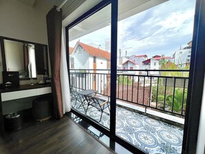 A room with a balcony, a sink, and a window with a view of buildings. - Paragon Noi Bai Hotel and Pool (Hanoi)