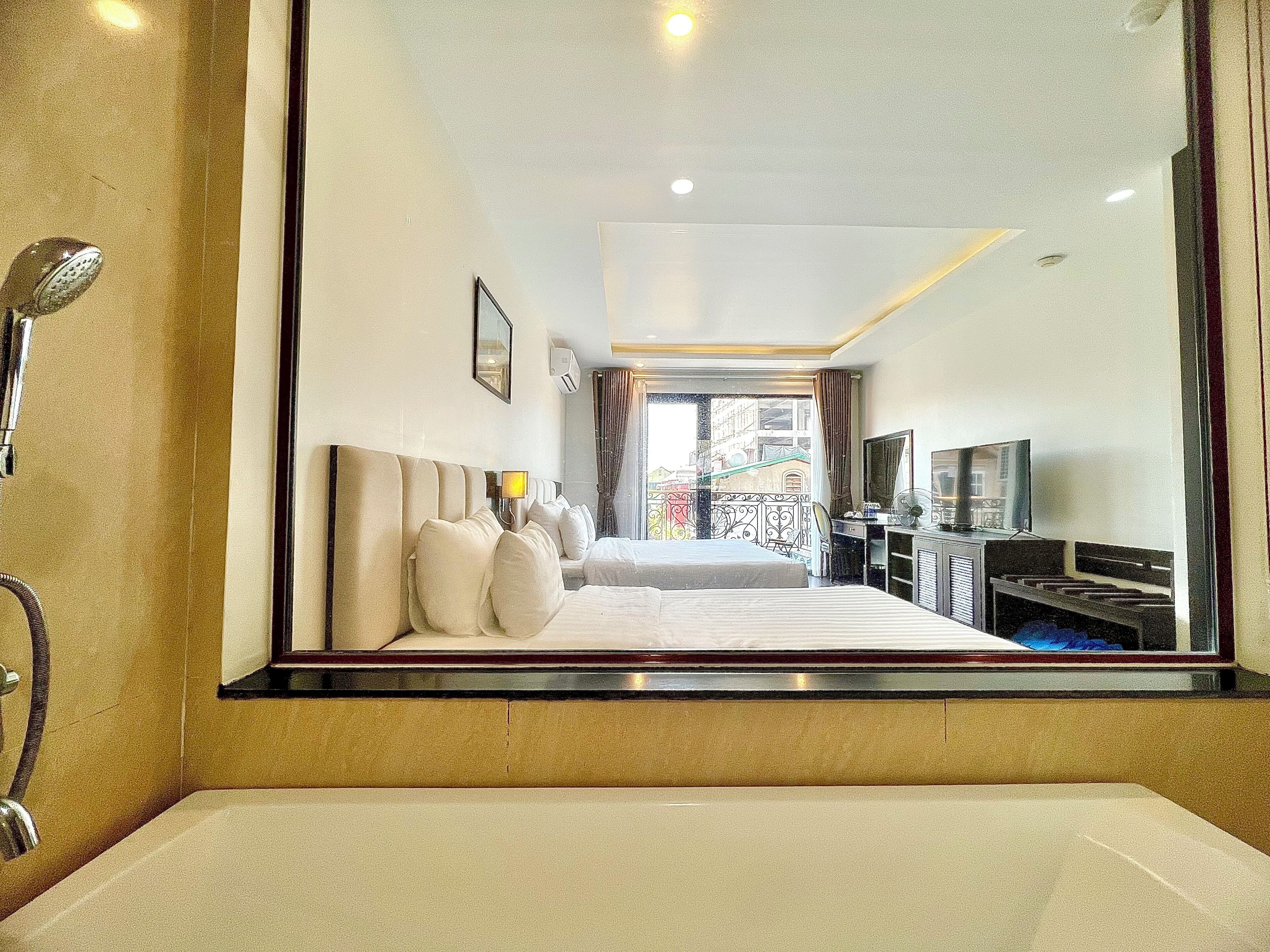 Habitación de hotel con una cama grande, un escritorio con computadora, un televisor y un baño con bañera y ducha.