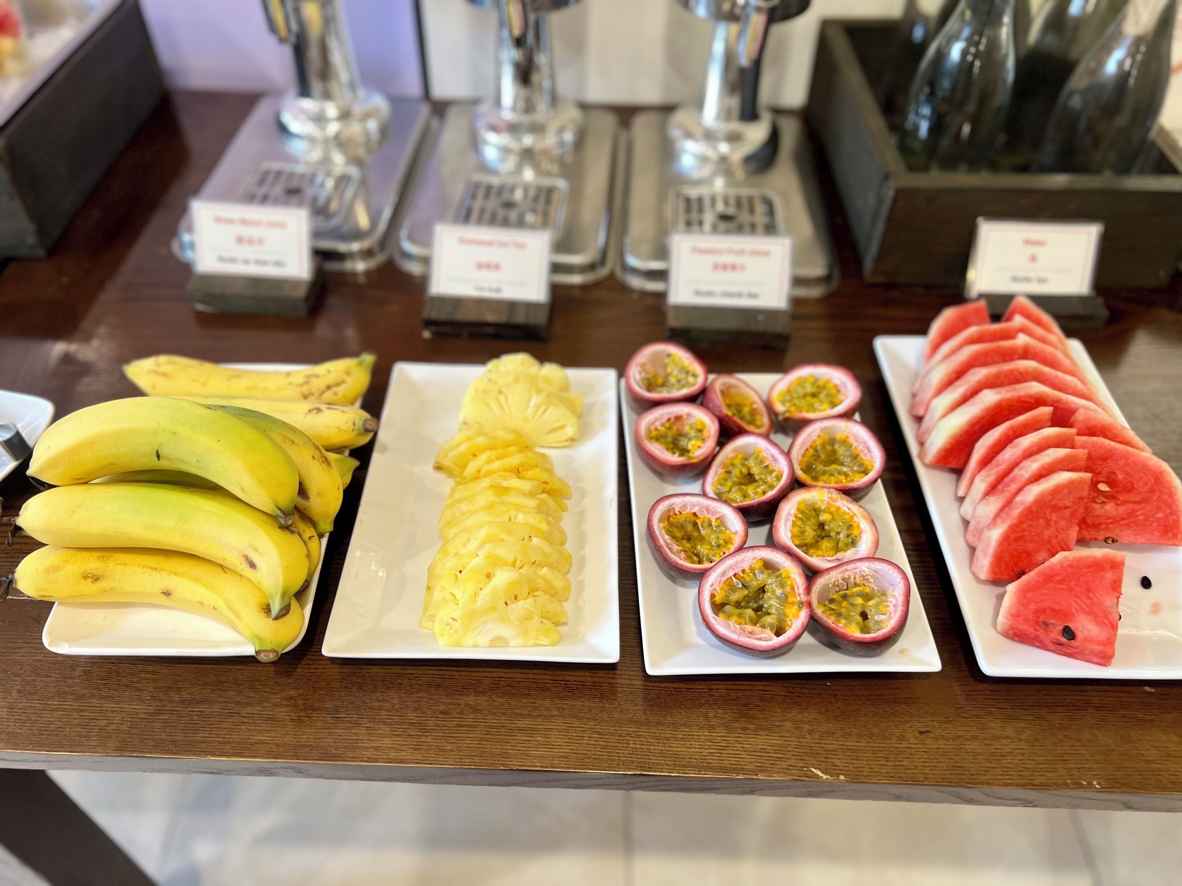 A buffet table with various fruits and a selection of bottled beverages.