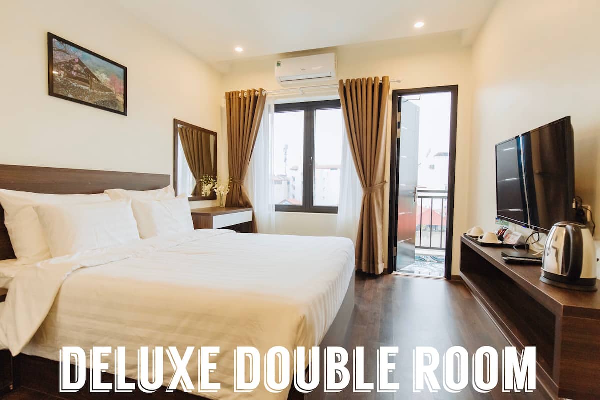 UNA HABITACIÓN DOBLE DE LUJO con una cama grande, televisor, cafetera y vistas al exterior.