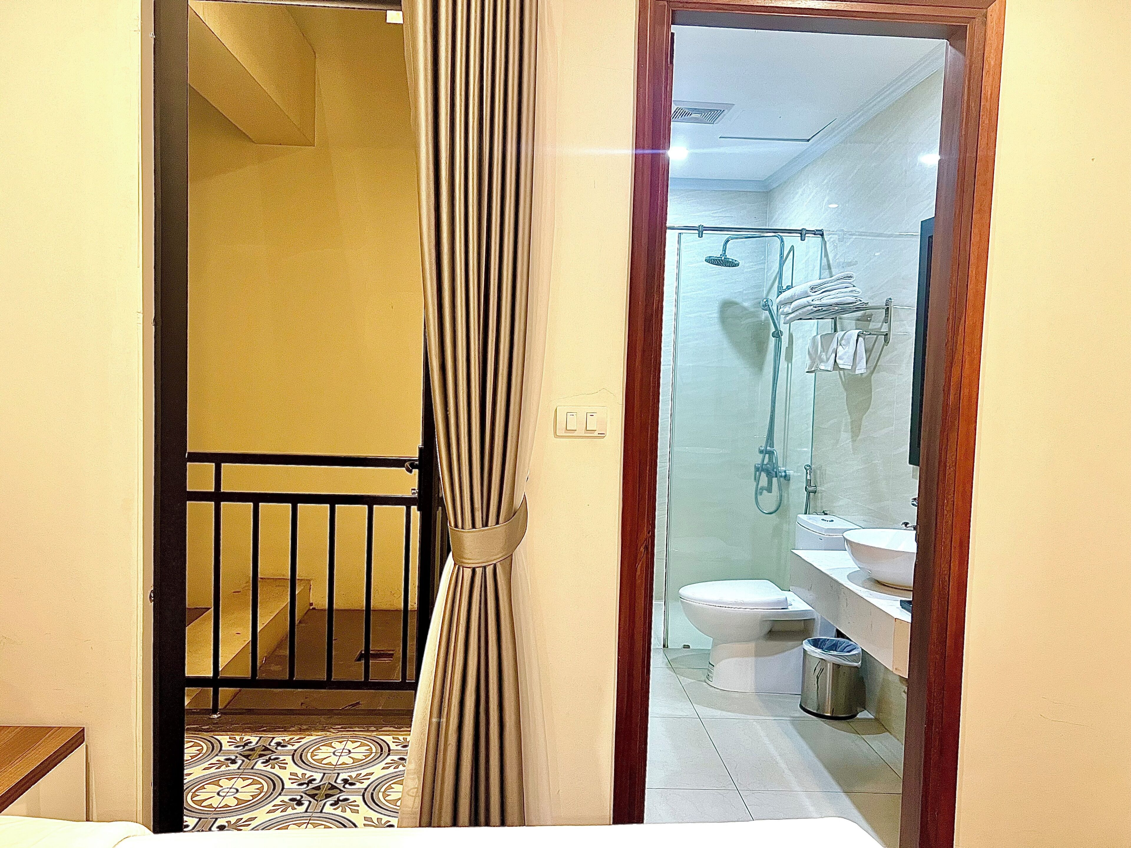 A hotel room with a bathroom that includes a shower, toilet, and sink.
