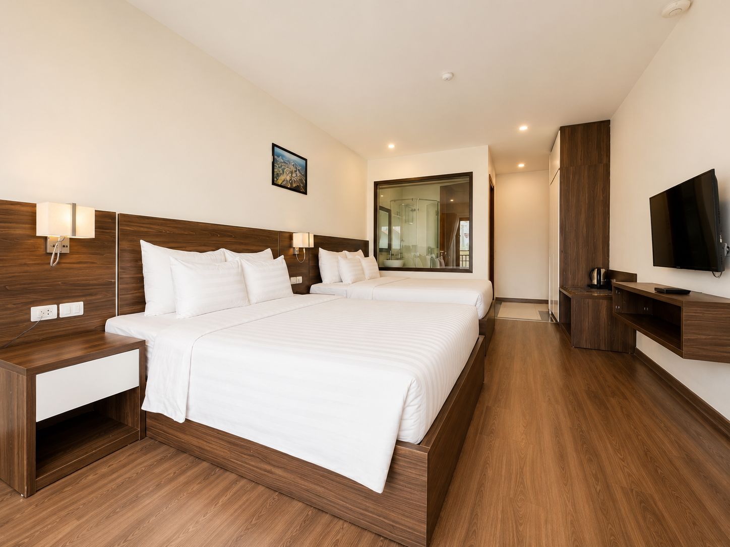 Habitación de hotel con una cama grande, mesitas de noche, televisión y baño visible a través de una puerta de vidrio.