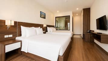 Habitación de hotel con una cama grande, mesitas de noche, televisión y baño visible a través de una puerta de vidrio.