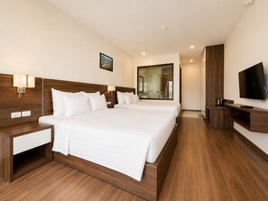 Habitación de hotel con una cama grande, mesitas de noche, televisión y baño visible a través de una puerta de vidrio.